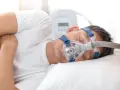 Mężczyzna śpi z maską CPAP, która pomaga mu oddychać podczas bezdechu sennego.