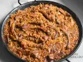 Arroz con costillas y champiñones en paellera, con granos de arroz dorados y trozos de carne jugosa.