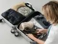 Pakowanie walizki: czarna kurtka, beżowa torebka, zielony biustonosz, czapka, buty, okulary i perfumy. Gotowi na podróż z tym bagażem!