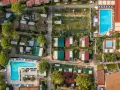 Widok z lotu ptaka na camping Toscolano: domki, baseny, przyczepy kempingowe i zielone tereny.