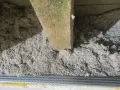 Luźna wełna celulozowa, widoczne nierówności i potencjalne wady izolacji pod drewnianą belką stropową.