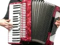 Ręce grają na czerwonym akordeonie, wydobywając dźwięki tego wspaniałego instrumentu.