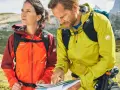 Wanderer prüfen die Route. Ihre wasserdichten Jacken schützen sie vor dem Wetter.