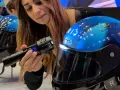 Donna mostra un casco da moto blu con visiera, evidenziando la sua importanza per la sicurezza. È bene che il casco sia dotato di visiera.
