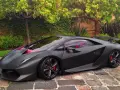 Matowy czarny Lamborghini Sesto Elemento z czerwonymi akcentami i wnętrzem, zaparkowany na brukowanej ścieżce wśród zieleni.