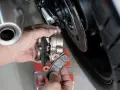 Mani che sostituiscono le pastiglie dei freni anteriori di una moto. Si valuta la durata pastiglie freni anteriori osservando l'usura.