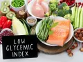 Łosoś, kurczak, warzywa, owoce i orzechy na tle tabliczki z napisem "Low Glycemic Index".