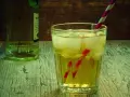 Orzeźwiający drink z lodem i słomką, idealny do przygotowania według przepisu na French Martini. Obok butelka alkoholu.