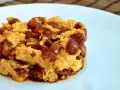 Deliciosa porción de duelos y quebrantos receta, con huevo revuelto y trozos de chorizo, servida en plato blanco.