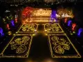 Magische Lichtershow im Tierpark Berlin: Verzauberte Gärten mit leuchtenden Mustern und farbig beleuchteten Bäumen vor einem prachtvollen Gebäude.