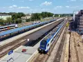 Widok z góry na dworzec kolejowy w Kielcach z pociągami na torach i placem budowy.