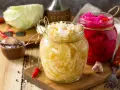 Frisch fermentiertes Sauerkraut im Glas, bereit für ein leckeres Sauerkraut Rezept. Daneben ein Glas mit Rotkohl.