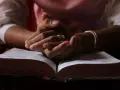 Hände ruhen auf einer geöffneten Bibel, ein Zeichen für tiefen Glauben und ein stilles Bibel Gebet.