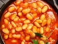 Pyszna fasolka po bretońsku przepis w garnku. Aromatyczne danie z białej fasoli w sosie pomidorowym, ozdobione natką pietruszki.