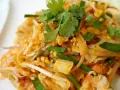 Pyszne phat thai z krewetkami, jajkiem i szczypiorkiem, udekorowane świeżą kolendrą.