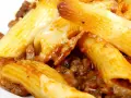 Macarrones con carne y queso fundido, cubiertos con salsa de tomate.