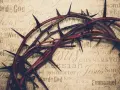 Dornenkrone auf Pergament mit Titeln wie "Jesus", "Messiah", "Savior". Sie symbolisiert die tiefe Jesus Christus Bedeutung und sein Leiden.