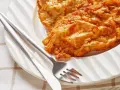 Złocisty kotlet słoneczny na białym talerzu, obok sztućce. Idealny na słoneczny dzień.