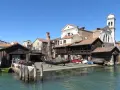 Lo squero di San Trovaso, con gondole in lavorazione e un campanile sullo sfondo, riflette la tradizione veneziana.