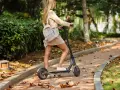 Ragazza su monopattino elettrico in un parco autunnale. Ricorda l'obbligo casco monopattino per la tua sicurezza.