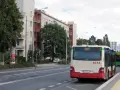 Autobus 8313 z numerem linii 836 czeka na przystanku. W tle budynki mieszkalne i drzewa.
