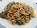 Un piatto invitante di tagliatella di mare con gamberi, cozze e vongole, condita con erbe fresche.