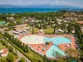 Widok z lotu ptaka na kompleks basenów i domków kempingowych w Sirmione. Woda lśni w słońcu, a ludzie cieszą się wakacjami na łonie natury.