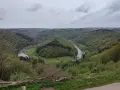 Malowniczy zakole rzeki w zielonych Ardenach, otoczone wzgórzami porośniętymi lasem.