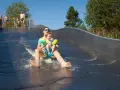 Vater und Sohn rutschen lachend die Wasserrutsche im Bostalsee Strandbad hinunter.