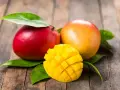 Dwa soczyste mango, jedno czerwone, drugie pomarańczowe, i jedno pokrojone w kostkę, idealne, gdy jest sezon na mango.
