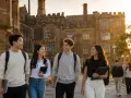 Grupa studentów idzie aleją uniwersytecką w blasku zachodzącego słońca. Marzą o studiach za granicą, ciesząc się wspólnym czasem.