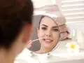 Kobieta w lustrze usuwa wąsik patyczkiem. Dowiedz się, jak usunąć wąsik żeby nie odrastał.