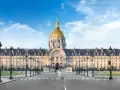 Imponente cúpula dorada del Hôtel des Invalides en París, con su fachada clásica y farolas a ambos lados de la avenida.