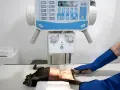 RTG kota w klinice weterynaryjnej. Zwierzę leży na stole pod aparatem rentgenowskim, a technik w ochronnych rękawach przygotowuje się do badania.