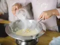 Préparation de la pâte à crêpes : on ajoute du sucre dans le bol avec un fouet. C'est la base de la recette des crêpes.