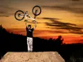 Tomas Lemoine triumphantly raises his bike against a fiery sunset, a champion on the dirt jump.