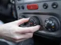 Dłoń reguluje pokrętłem nawiewu w samochodzie, ustawiając temperaturę. 4h0121671d.