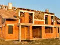 Budowa domu energooszczędnego z cegły ceramicznej. Widoczny szkielet dachu i otwory okienne.