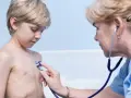 Lekarz osłuchuje klatkę piersiową chłopca, diagnozując zapalenie oskrzeli u dzieci.