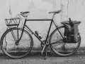 Svart cykel med korg fram och väska bak, redo att montera pakethållare för äventyr.