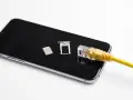 Smartfon z kartą SIM i tacką, podłączony żółtym kablem sieciowym. Możliwość play multisim.