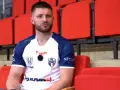 Marcel Sroczyk, zawodnik MKS Kalisz, siedzi na czerwonych trybunach.