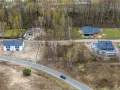 Widok z lotu ptaka na budowę domów jednorodzinnych, tworzących nowy plan ogólny gminy. Widać domy w różnym stanie budowy i drogę.