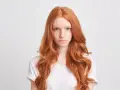 Dziewczyna z burzą rudych włosów, piegami i niebieskimi oczami patrzy prosto przed siebie.