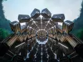 Un tunnel caleidoscopico di bauli Louis Vuitton, un omaggio al fondatore, con uno sfondo di montagne verdi e cielo azzurro.