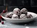 En skål med chokladbollar, perfekta för ett enkelt chokladbollar recept. Körsbär och florsocker ger en festlig touch.
