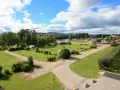 Vacker vy över svegs camping med husbilar, stugor och en sjö i bakgrunden under en molnig himmel.