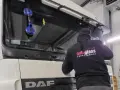 Montaż szyby w traktorze DAF. Pracownik firmy "Autoglass Łukaszewski" używa przyssawek do bezpiecznego osadzenia nowej szyby.
