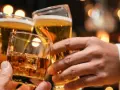 Trzy dłonie wznoszą toast: jedna z whisky na lodzie, dwie z piwem. Lepiej 2 drinki czy 2 piwa?
