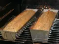 Dwa bochenki chleba dukana pieką się w piekarniku, w metalowych formach.